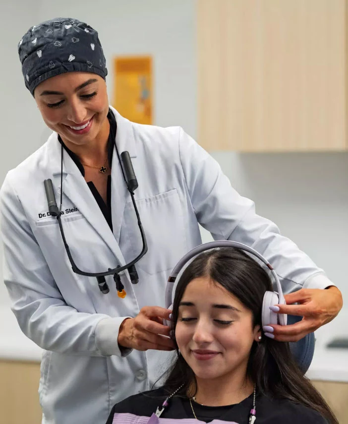 A SmilePro Dental clinician placing noise-cancelling headphones on a calm, relaxed patient during a sedation visit