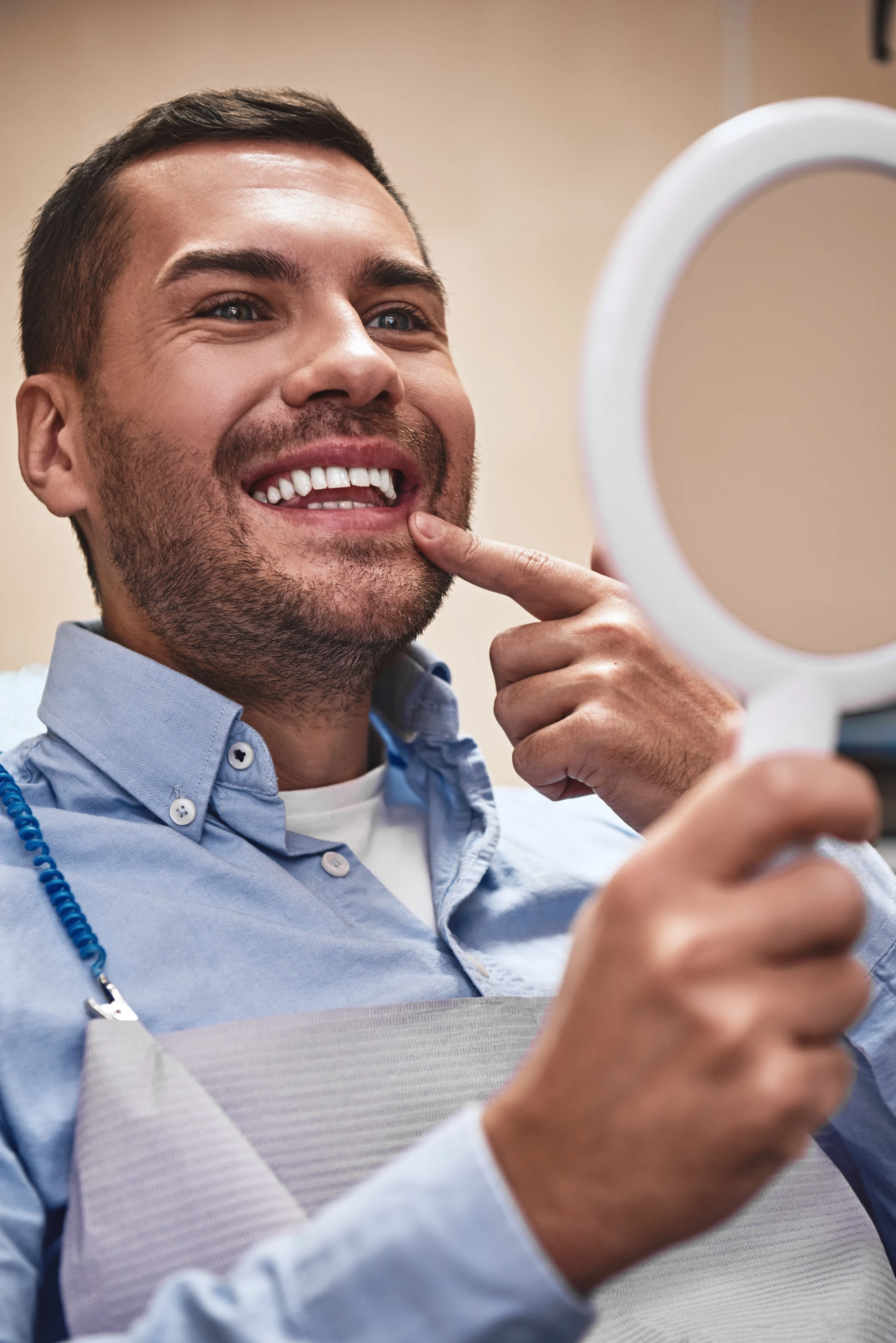 A patient smiling at his reflection after dental treatment