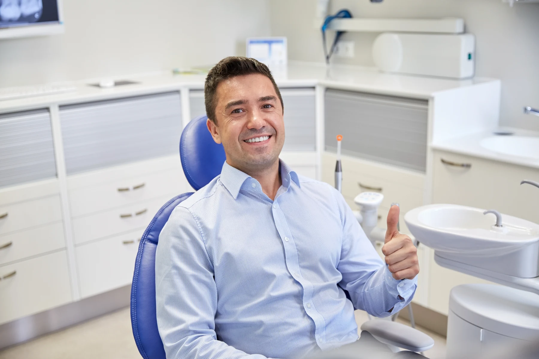 A relaxed patient giving a thumbs-up in the dental chair