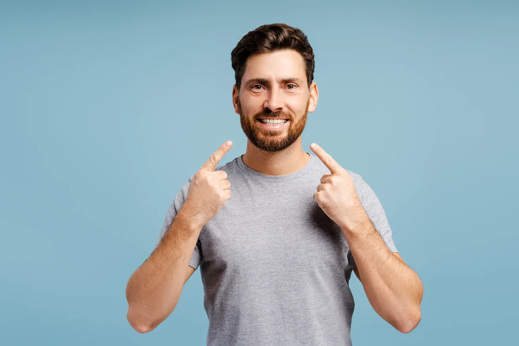 A smiling man pointing to his teeth — Composite Bonding at SmilePro Dental