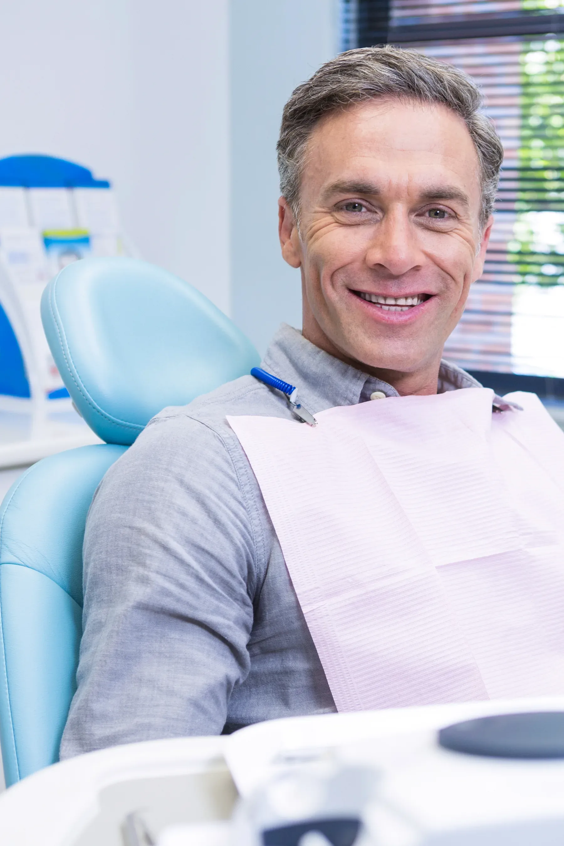 A smiling grey-haired man in the dental chair — Dentures at SmilePro Dental