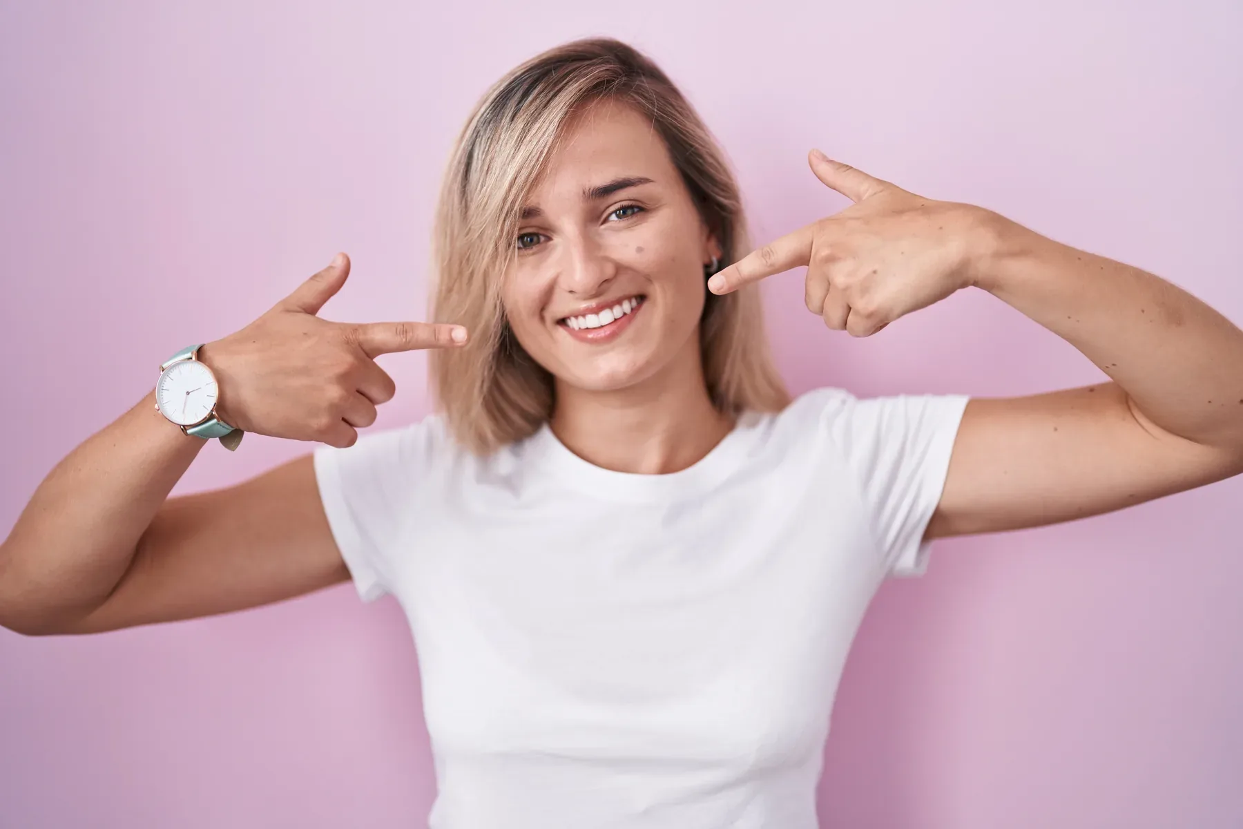 A smiling woman pointing to her teeth — Exams & Cleanings at SmilePro Dental