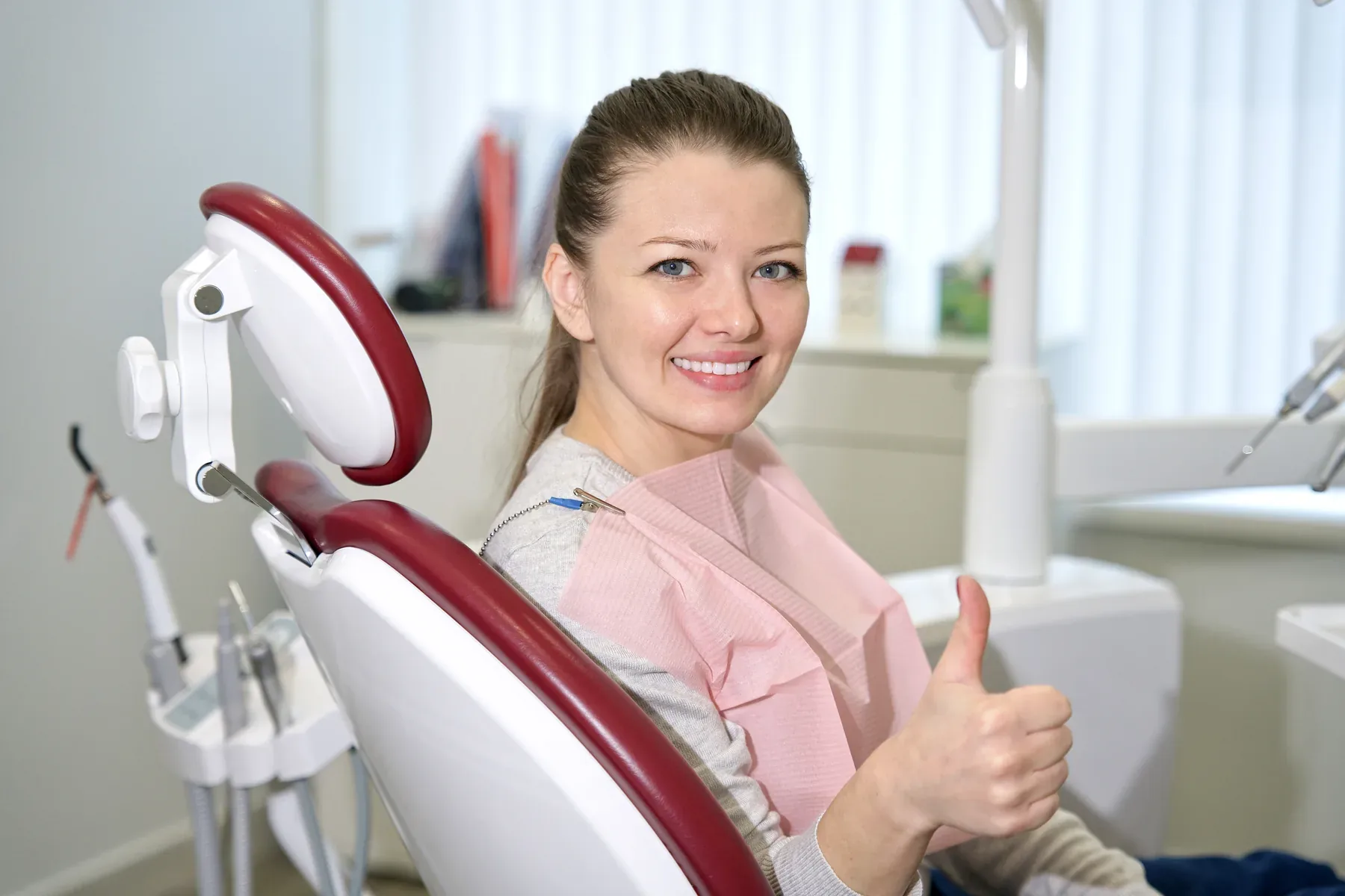 A smiling woman giving a thumbs-up in the dental chair