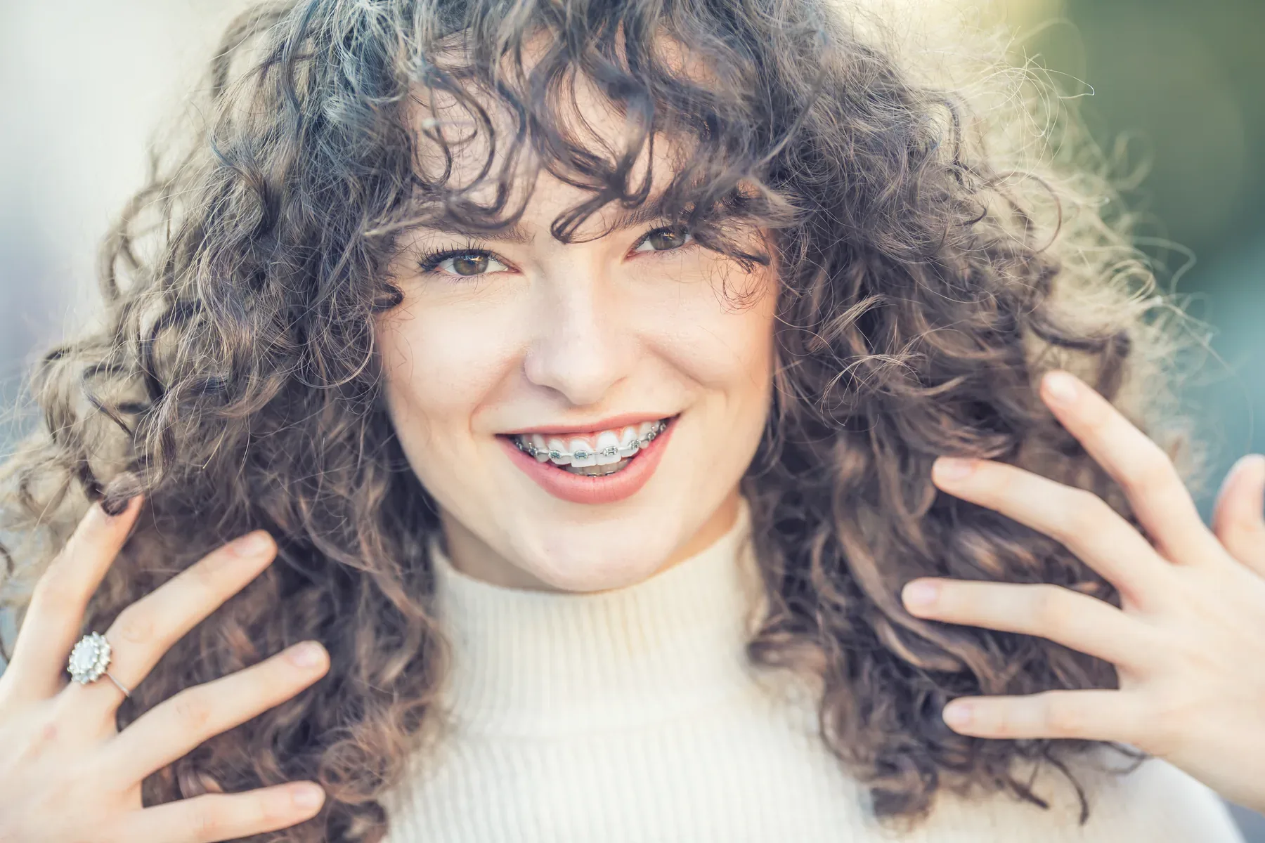A smiling woman with braces and curly hair — Braces at SmilePro Dental